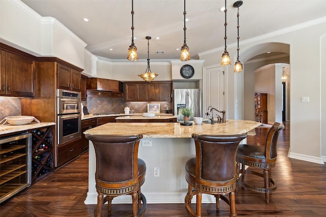 27435 Waterfall Hill Pkwy, Spicewood, TX 78669 - kitchen with stainless steel appliances, a breakfast bar area, recessed lighting, arched walkways, and beverage cooler