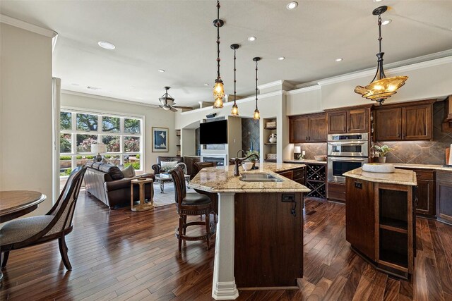 27435 Waterfall Hill Pkwy, Spicewood, TX 78669 - kitchen featuring ornamental molding, a sink, open floor plan, double oven, and a kitchen island with sink