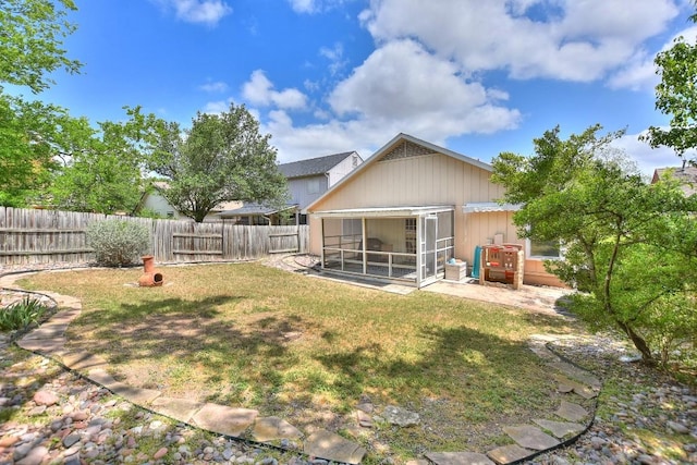 back of house with a fenced backyard, a sunroom, and a lawn