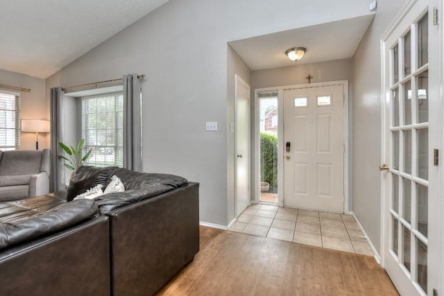 entrance foyer featuring lofted ceiling, light wood-type flooring, plenty of natural light, and baseboards