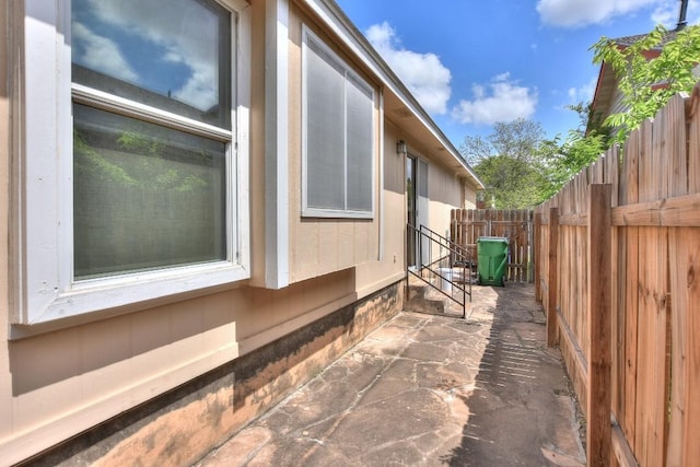 view of property exterior featuring fence, entry steps, and a patio