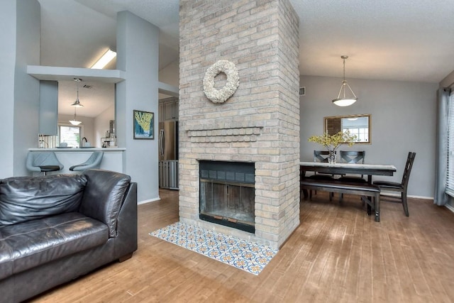 living room with lofted ceiling, wood finished floors, and a brick fireplace