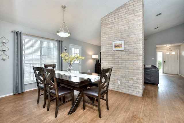 dining room featuring lofted ceiling, wood finished floors, visible vents, and a healthy amount of sunlight