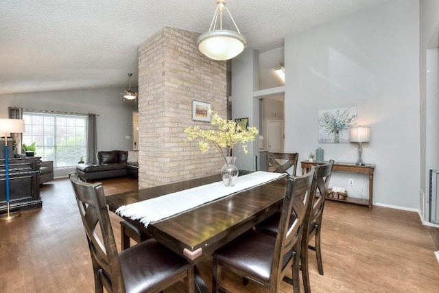 dining area with a textured ceiling, a ceiling fan, high vaulted ceiling, and wood finished floors