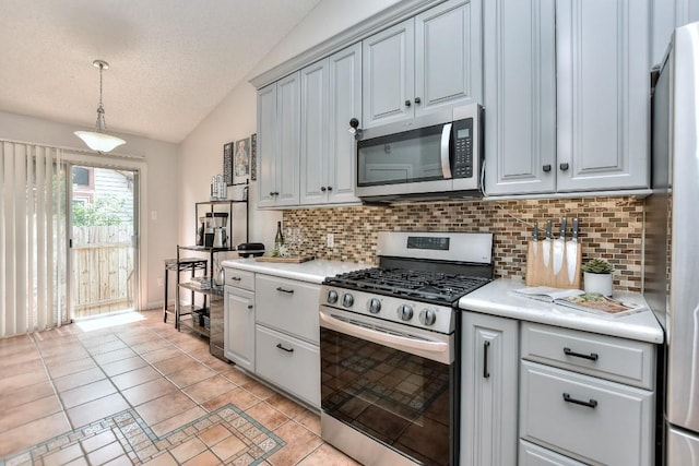 kitchen with stainless steel appliances, light countertops, vaulted ceiling, and backsplash