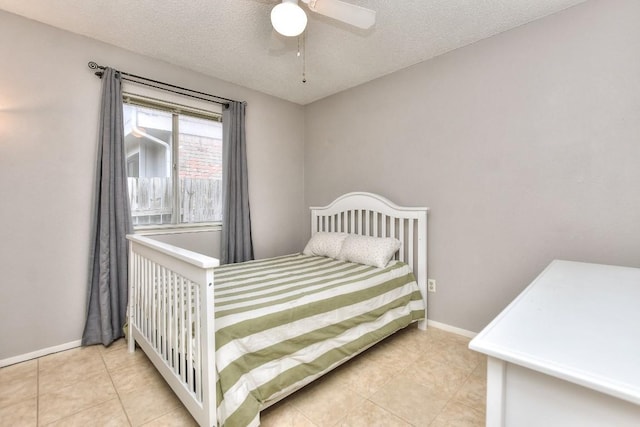 bedroom featuring a textured ceiling, a ceiling fan, tile patterned flooring, and baseboards