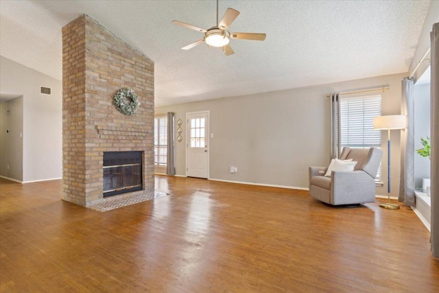 2203 Nathan Dr, Austin, TX 78728 - living area featuring ceiling fan, wood finished floors, a fireplace, a textured ceiling, and high vaulted ceiling