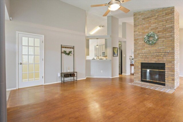 2203 Nathan Dr, Austin, TX 78728 - unfurnished living room featuring a ceiling fan, wood finished floors, a brick fireplace, and a towering ceiling