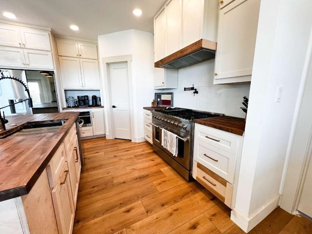 kitchen featuring wood counters, custom exhaust hood, double oven range, and a sink