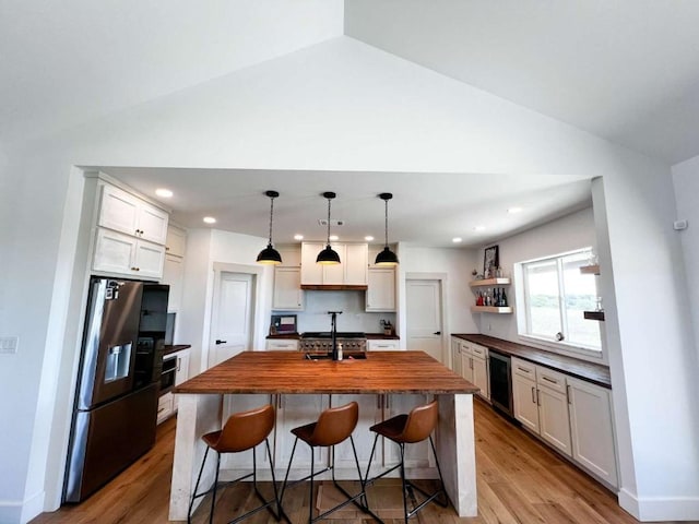 kitchen featuring lofted ceiling, wood finished floors, butcher block countertops, and stainless steel fridge