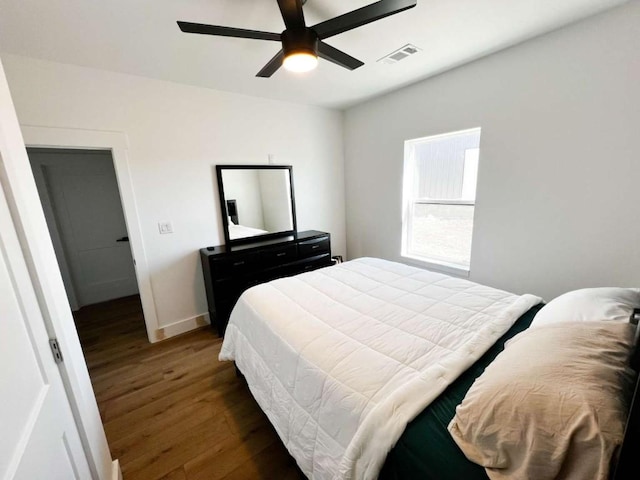 bedroom featuring baseboards, wood finished floors, visible vents, and ceiling fan