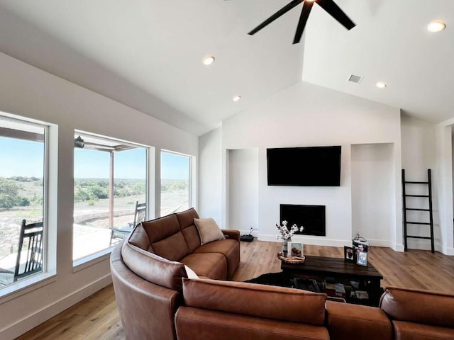 living area featuring a fireplace, visible vents, ceiling fan, and plenty of natural light