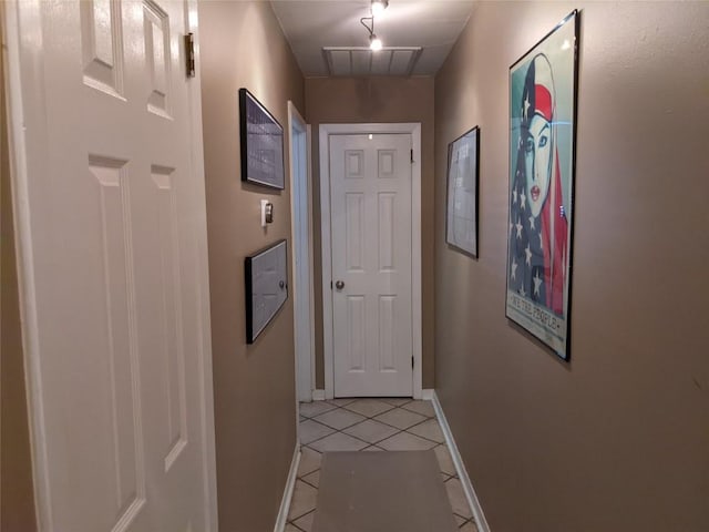 hallway with attic access, baseboards, visible vents, and light tile patterned floors