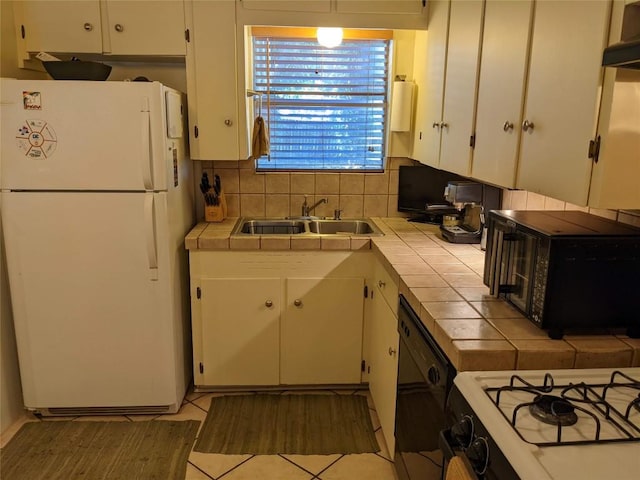 kitchen with white cabinets, tile countertops, a sink, and black appliances