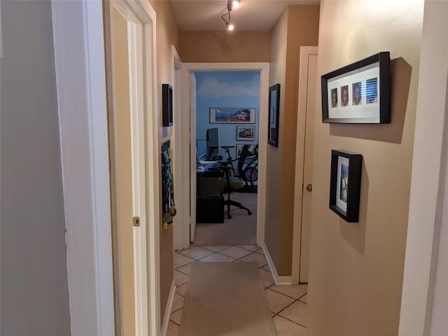hall with rail lighting, light carpet, baseboards, and light tile patterned floors