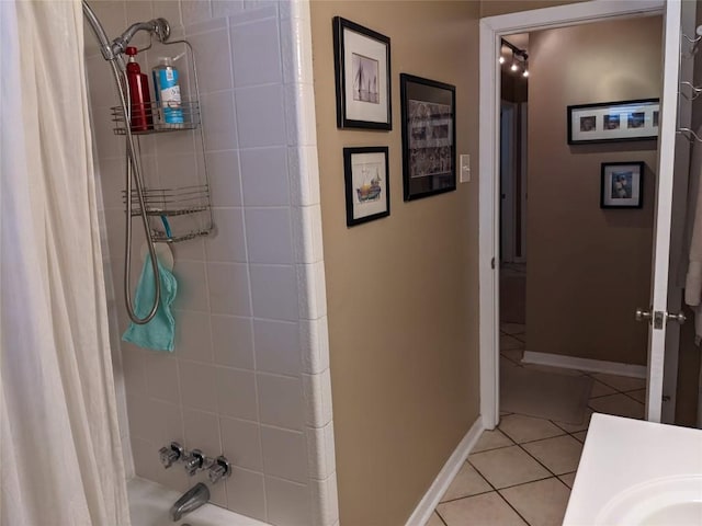 full bathroom featuring shower / tub combo with curtain, tile patterned flooring, baseboards, and a sink