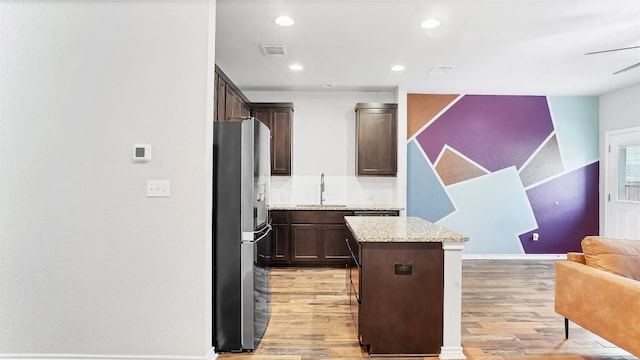 1837 Artesian Springs Xing, Leander, TX 78641 - kitchen with light wood finished floors, stainless steel fridge with ice dispenser, dark brown cabinets, visible vents, and a center island