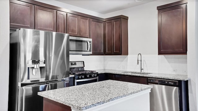1837 Artesian Springs Xing, Leander, TX 78641 - kitchen featuring stainless steel appliances, a sink, dark brown cabinets, light stone countertops, and a kitchen island