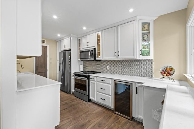 9 Stoney Creek Cv, Lakeway, TX 78734 - kitchen featuring appliances with stainless steel finishes, wine cooler, decorative backsplash, dark wood-style floors, and light countertops