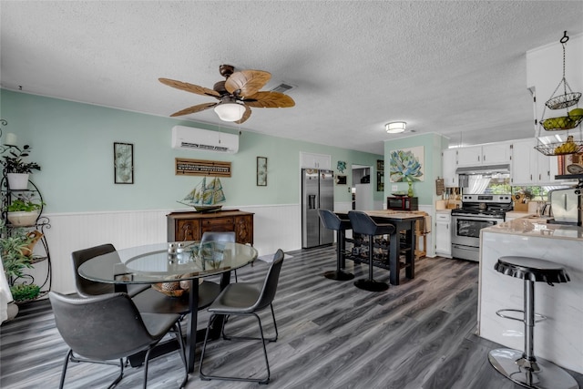 dining room featuring a textured ceiling, visible vents, a wall unit AC, and wainscoting