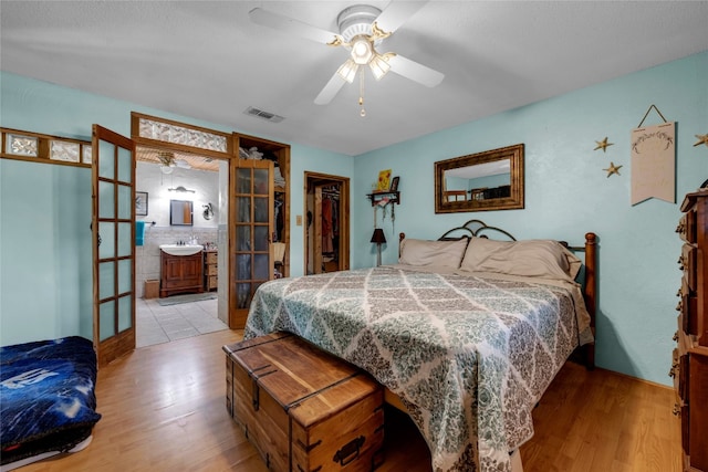 bedroom featuring french doors, wood finished floors, visible vents, and a sink