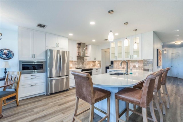 219 Quarry Ln, Liberty Hill, TX 78642 - kitchen featuring a sink, glass insert cabinets, stainless steel appliances, wall chimney exhaust hood, and a peninsula