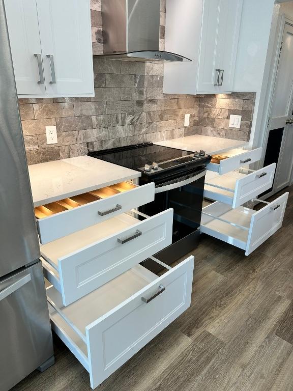 219 Quarry Ln, Liberty Hill, TX 78642 - kitchen with black / electric stove, light countertops, backsplash, wall chimney range hood, and freestanding refrigerator
