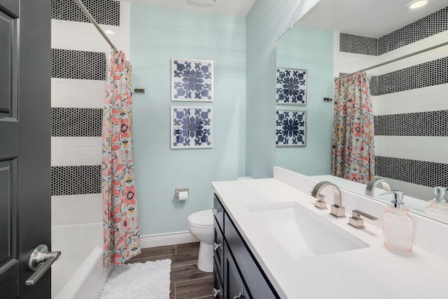 full bath with toilet, wood finished floors, tiled shower / bath, vanity, and baseboards