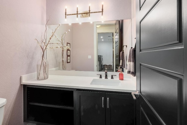 bathroom featuring a textured wall, toilet, and vanity
