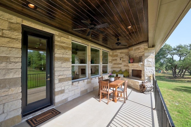 view of patio featuring an outdoor stone fireplace, a ceiling fan, and visible vents