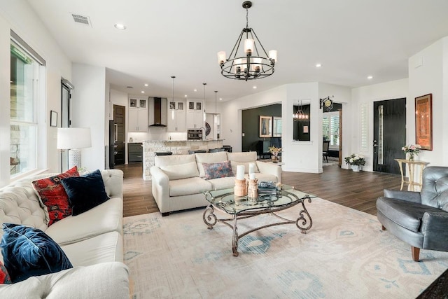 living area with recessed lighting, light wood-type flooring, visible vents, and an inviting chandelier