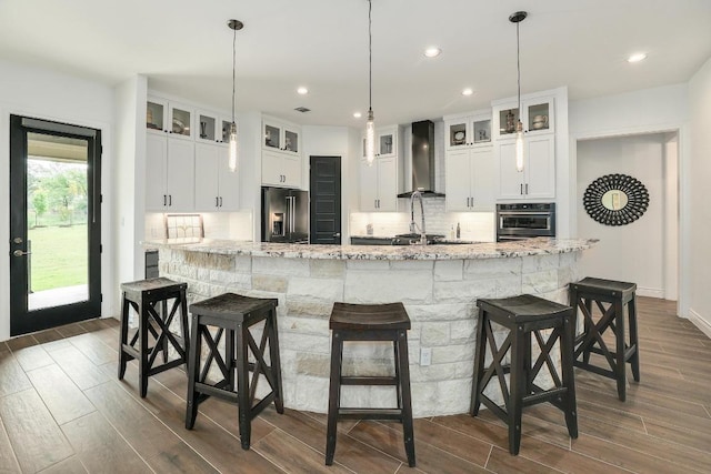 kitchen with wall chimney exhaust hood, wall oven, high quality fridge, and dark wood-style flooring