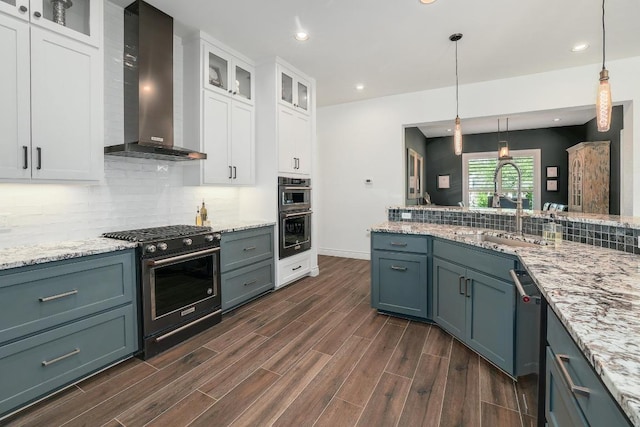 kitchen with dark wood finished floors, backsplash, wall chimney range hood, appliances with stainless steel finishes, and white cabinetry
