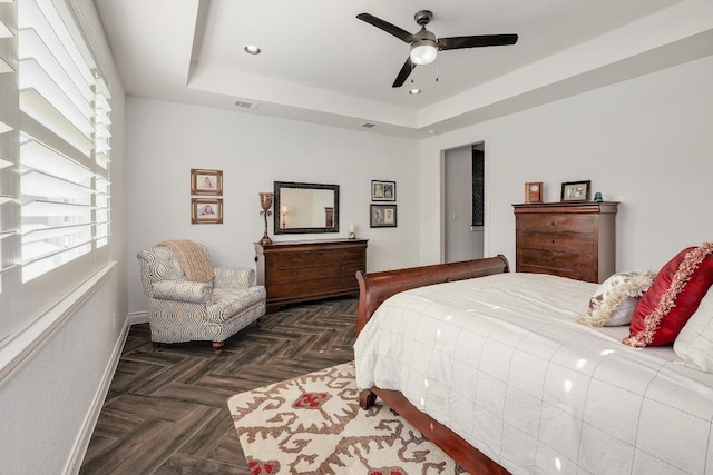 bedroom with visible vents, a ceiling fan, baseboards, and a raised ceiling