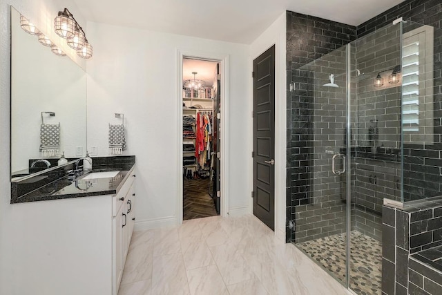 bathroom with a shower stall, a spacious closet, vanity, marble finish floor, and baseboards
