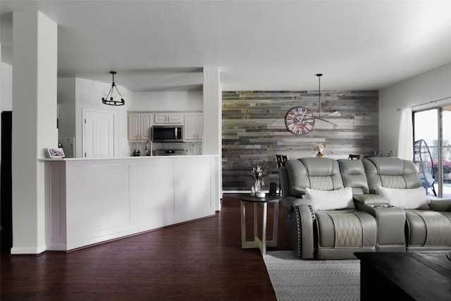 living room featuring wood walls, an accent wall, and dark wood-type flooring
