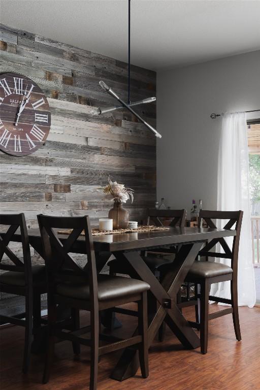 dining room with wooden walls and wood finished floors