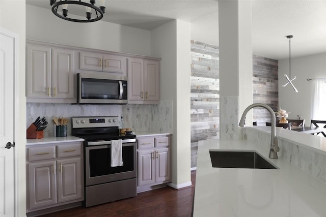 kitchen featuring dark wood finished floors, stainless steel appliances, light countertops, a sink, and tasteful backsplash