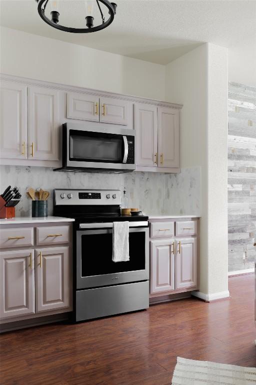 kitchen featuring stainless steel appliances, light countertops, dark wood finished floors, and tasteful backsplash