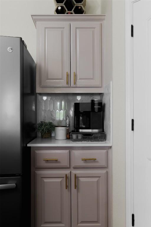 bar featuring tasteful backsplash and freestanding refrigerator