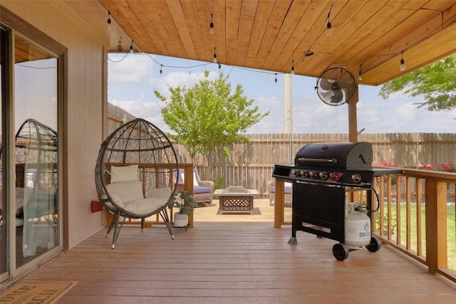 deck with a fenced backyard, an outdoor fire pit, and area for grilling