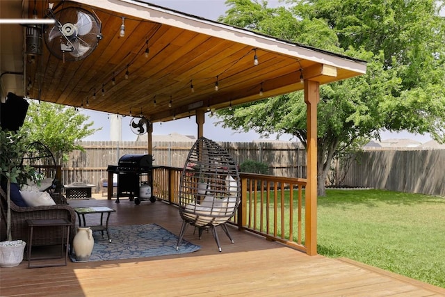 wooden terrace featuring grilling area, a lawn, and a fenced backyard