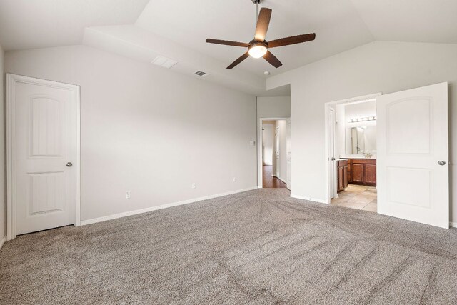 unfurnished bedroom with vaulted ceiling, visible vents, baseboards, light colored carpet, and ensuite bathroom