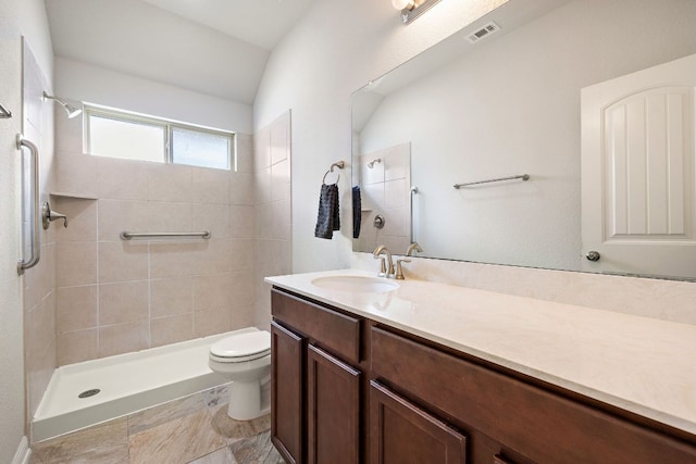 bathroom with a tile shower, visible vents, toilet, and vanity