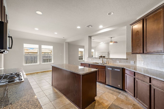 kitchen with stainless steel appliances, a center island, a sink, visible vents, and ceiling fan