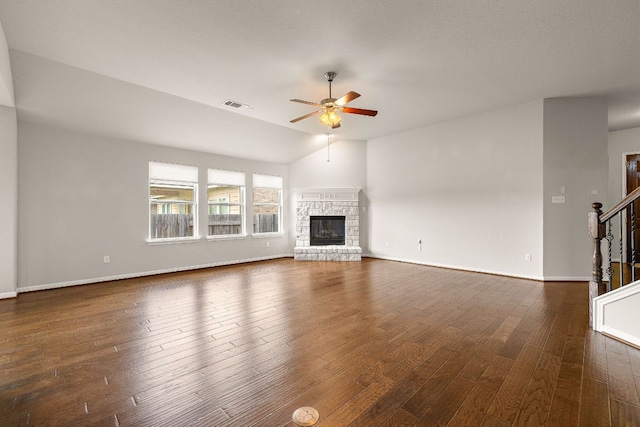 unfurnished living room with baseboards, visible vents, stairway, ceiling fan, and a stone fireplace