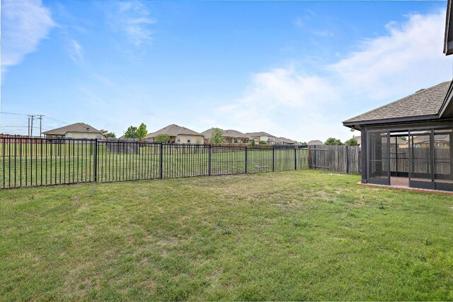 view of yard featuring a fenced backyard and a sunroom