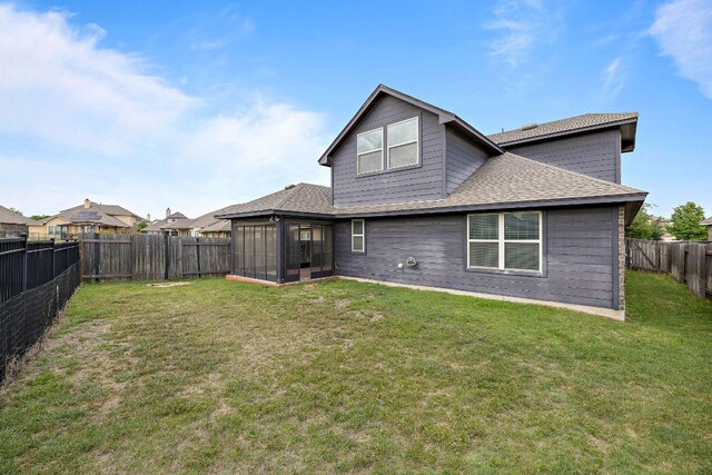 back of property featuring a shingled roof, a lawn, a fenced backyard, and a sunroom