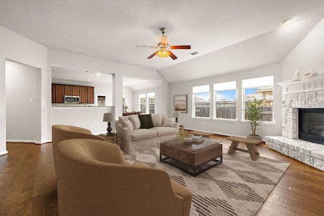 living area featuring a fireplace, visible vents, ceiling fan, and dark wood finished floors