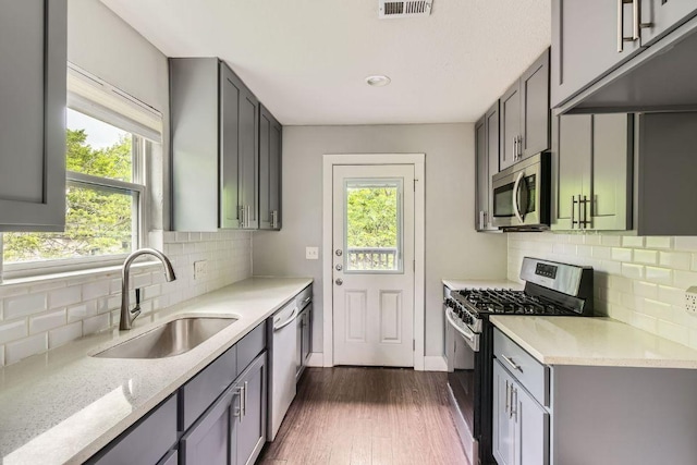 kitchen featuring dark wood-type flooring, a wealth of natural light, appliances with stainless steel finishes, and a sink